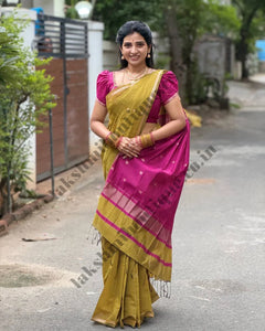 A woman wearing a navy blue and red patterned saree stands in a garden courtyard in front of a small white and red deity shrine.