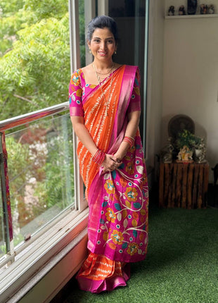 Woman in a colorful saree standing by a window with greenery outside
