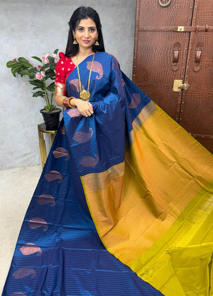A woman showcasing a blue and yellow saree with a floral design, presented by LAKSHMI BOUTIQUE.