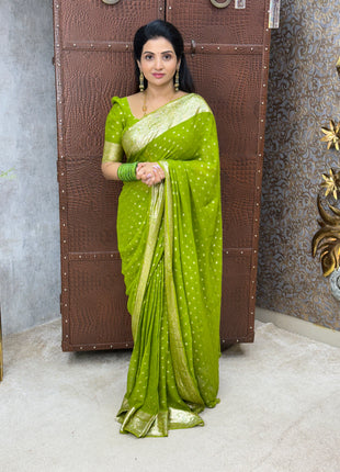 Woman wearing a green saree with a white border in an indoor setting.