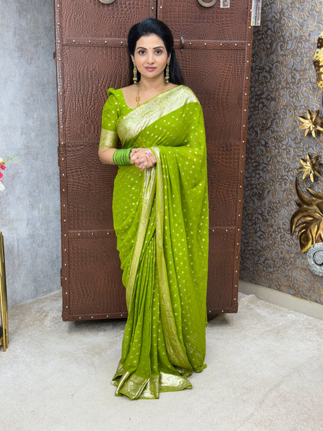 Woman wearing a green saree with a white border in an indoor setting.